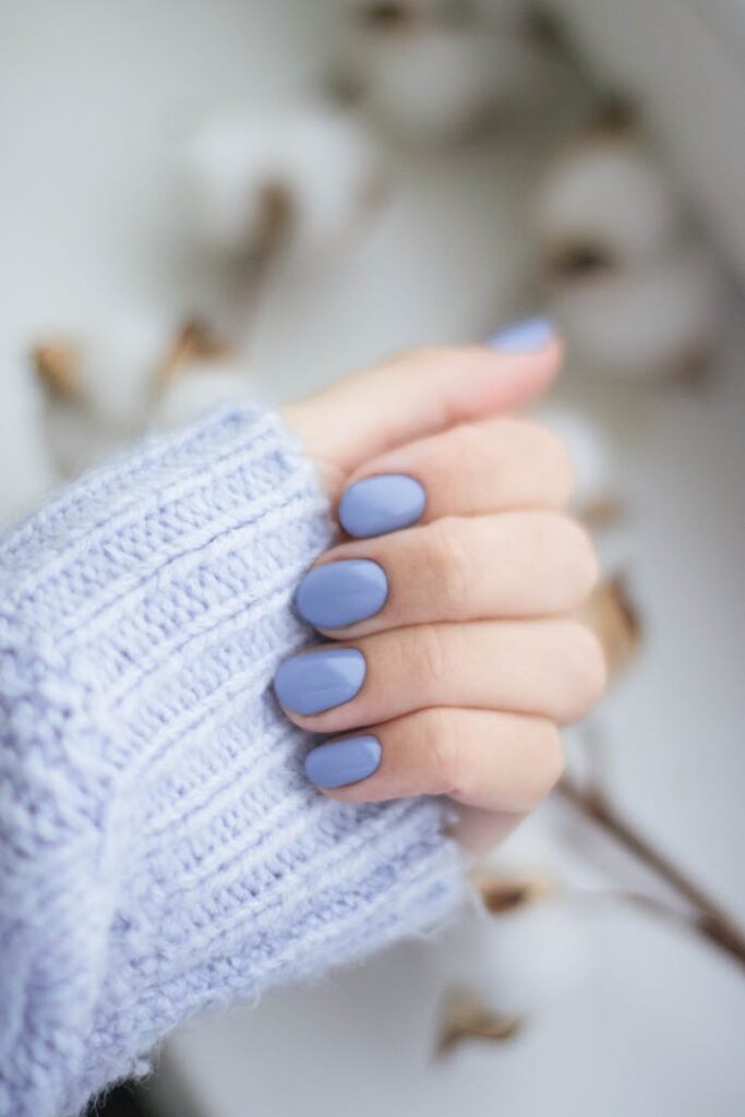 pexels photo 1839711 A close-up of a woman's hand with purple manicured nails and knitwear, showcasing trendy fashion.