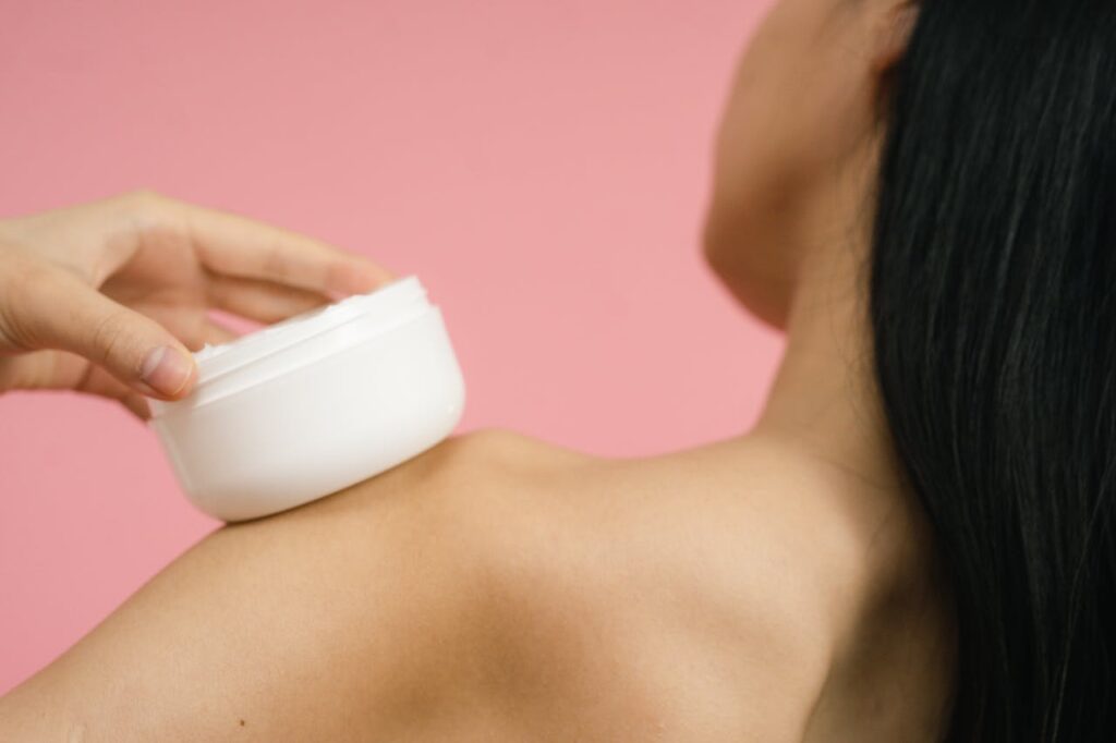 pexels photo 9774868 Close-up of a woman applying cosmetic cream to shoulder. Ideal for skincare and beauty themes.